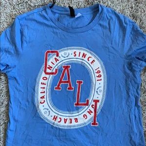 BLUE SHIRT WITH THE WORD CALI ON IT.